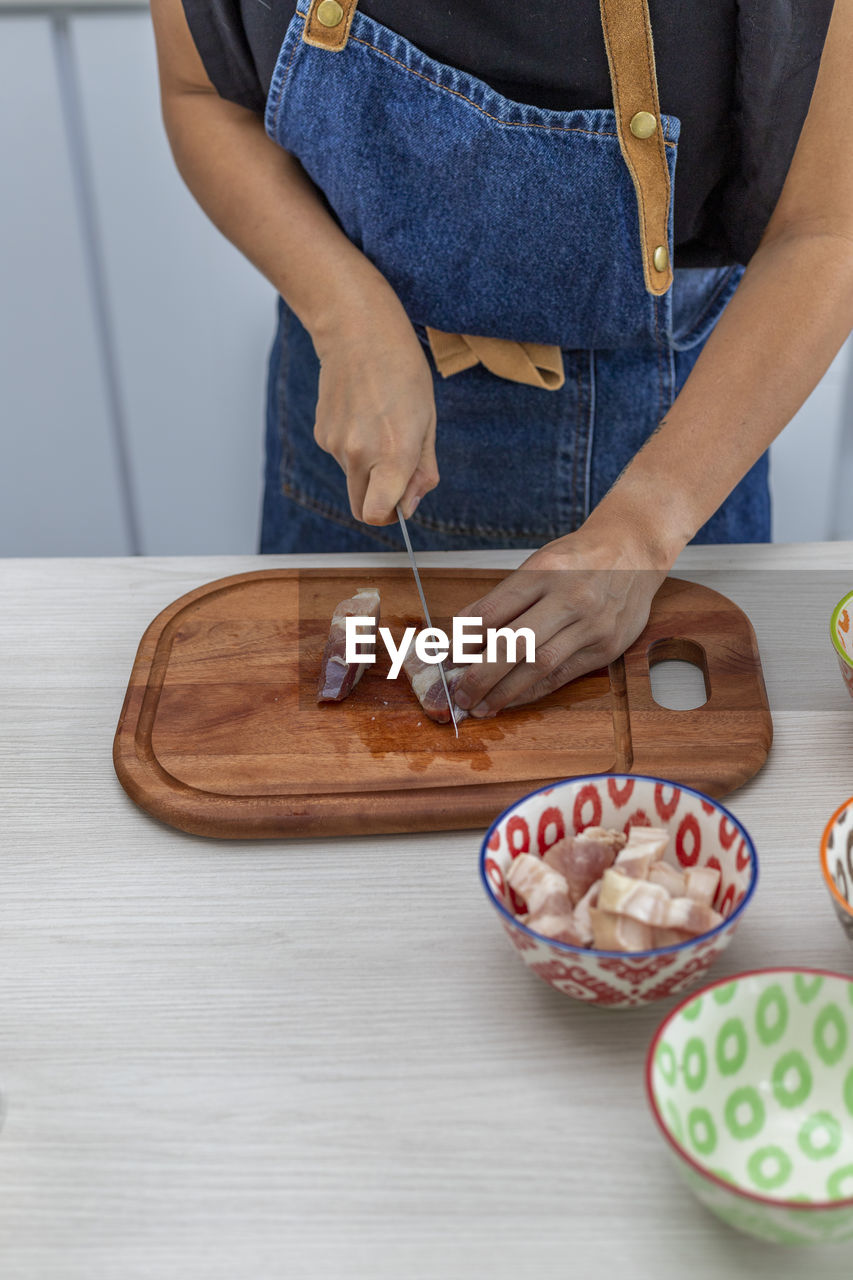 Vertical shot of a woman in the kitchen cutting meat for dinner