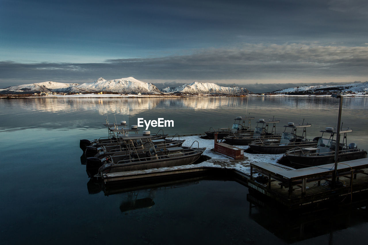 Boats moored at harbor against sky during winter