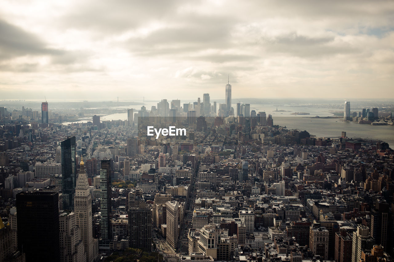 Aerial view of buildings in city against cloudy sky