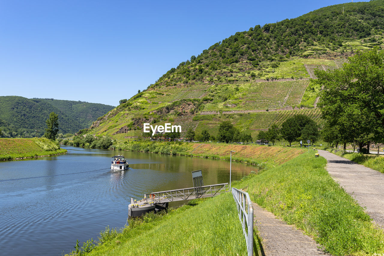 Beautiful view of a river flowing between grape hills in western germany, a motorboat visible.