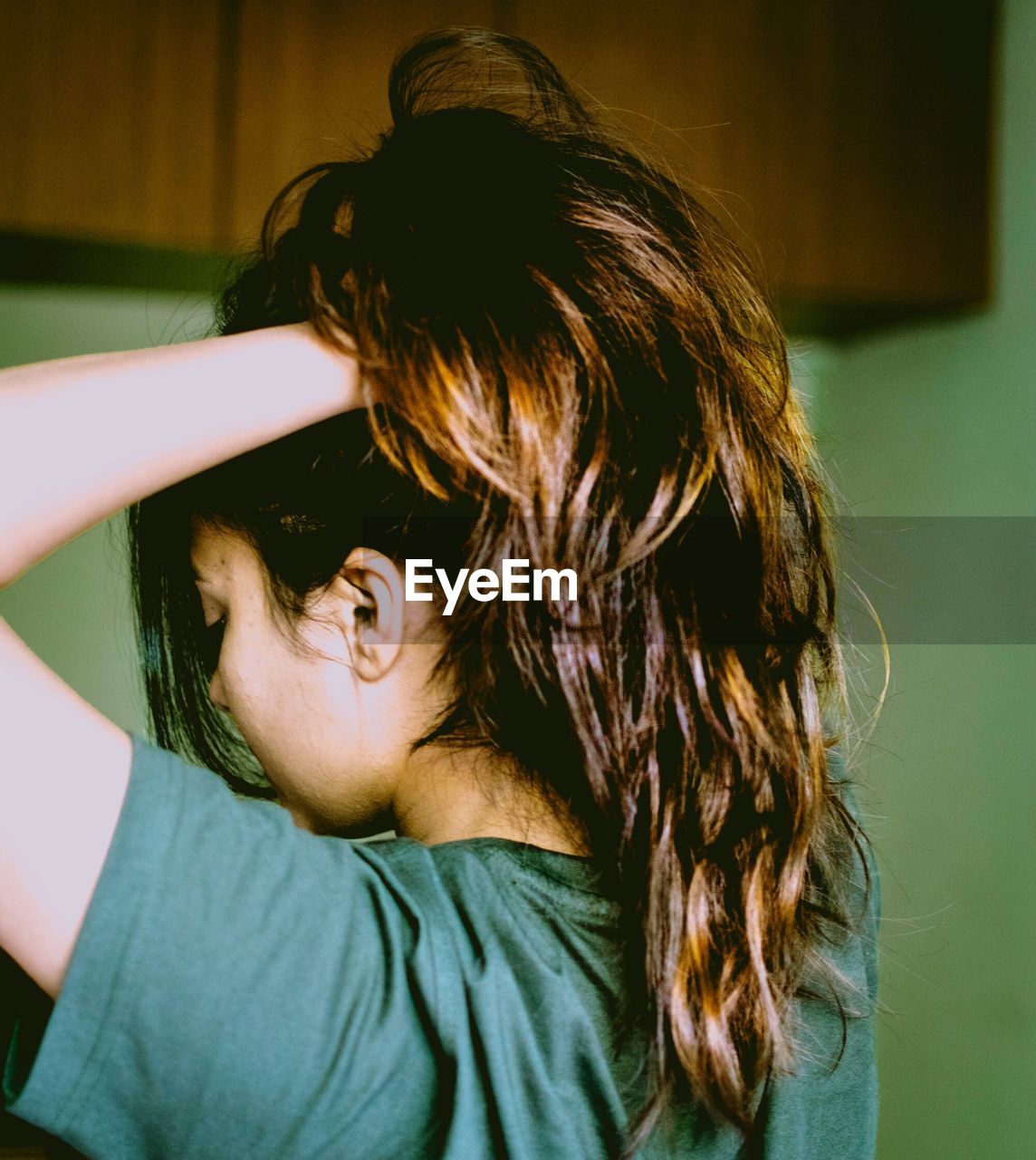 Woman with hand in hair standing at home