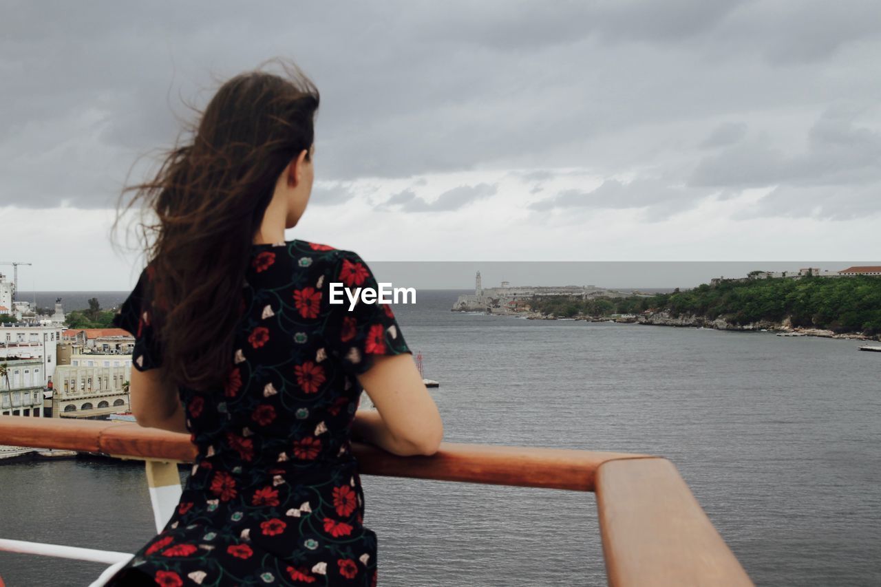 Woman standing on river with city in background