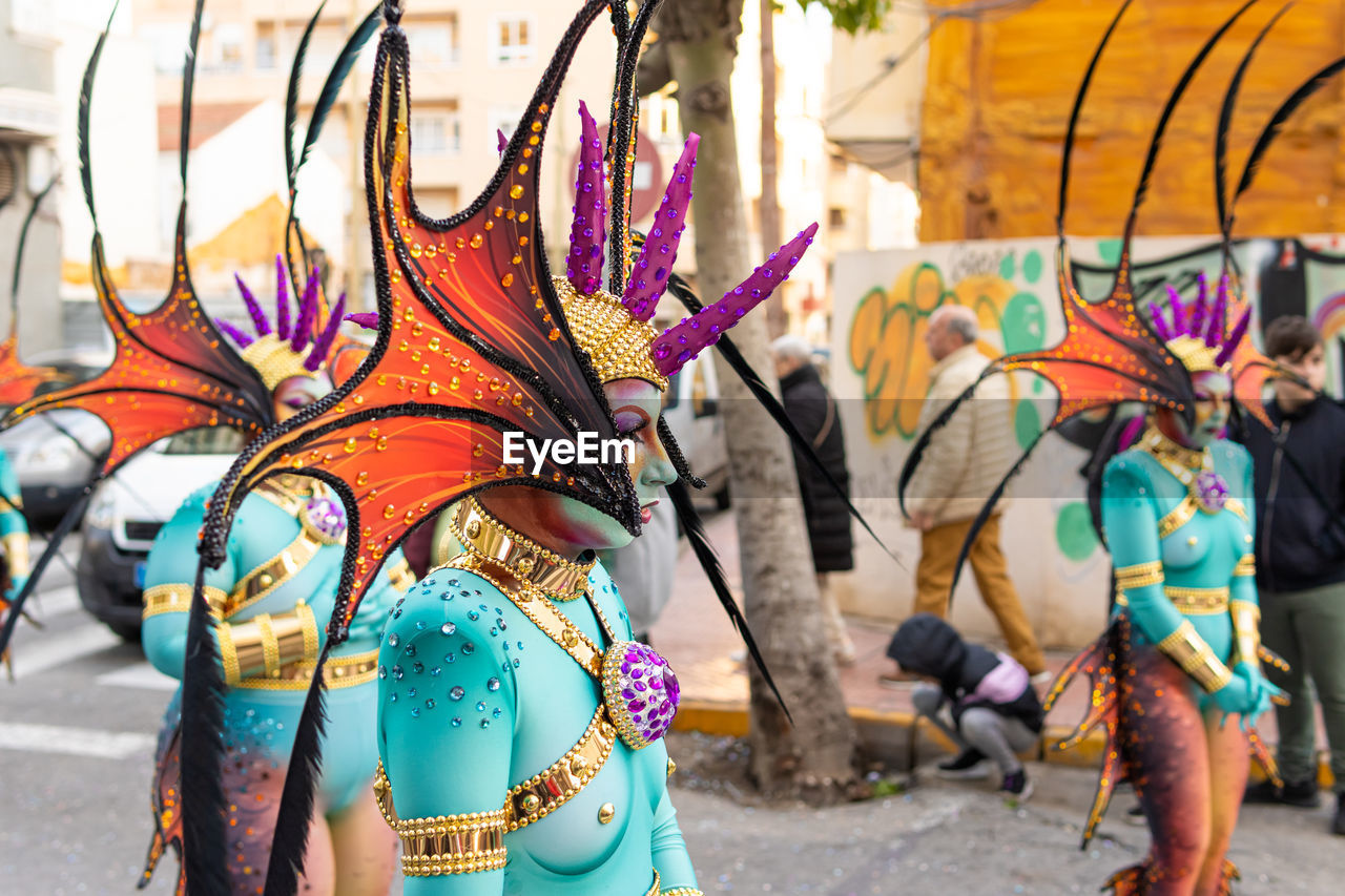 festival, multi colored, carnival, creativity, tradition, city, arts culture and entertainment, day, street, representation, animal representation, architecture, traditional clothing, outdoors, event, adult, clothing, celebration, focus on foreground, person, group of people, dancing, costume