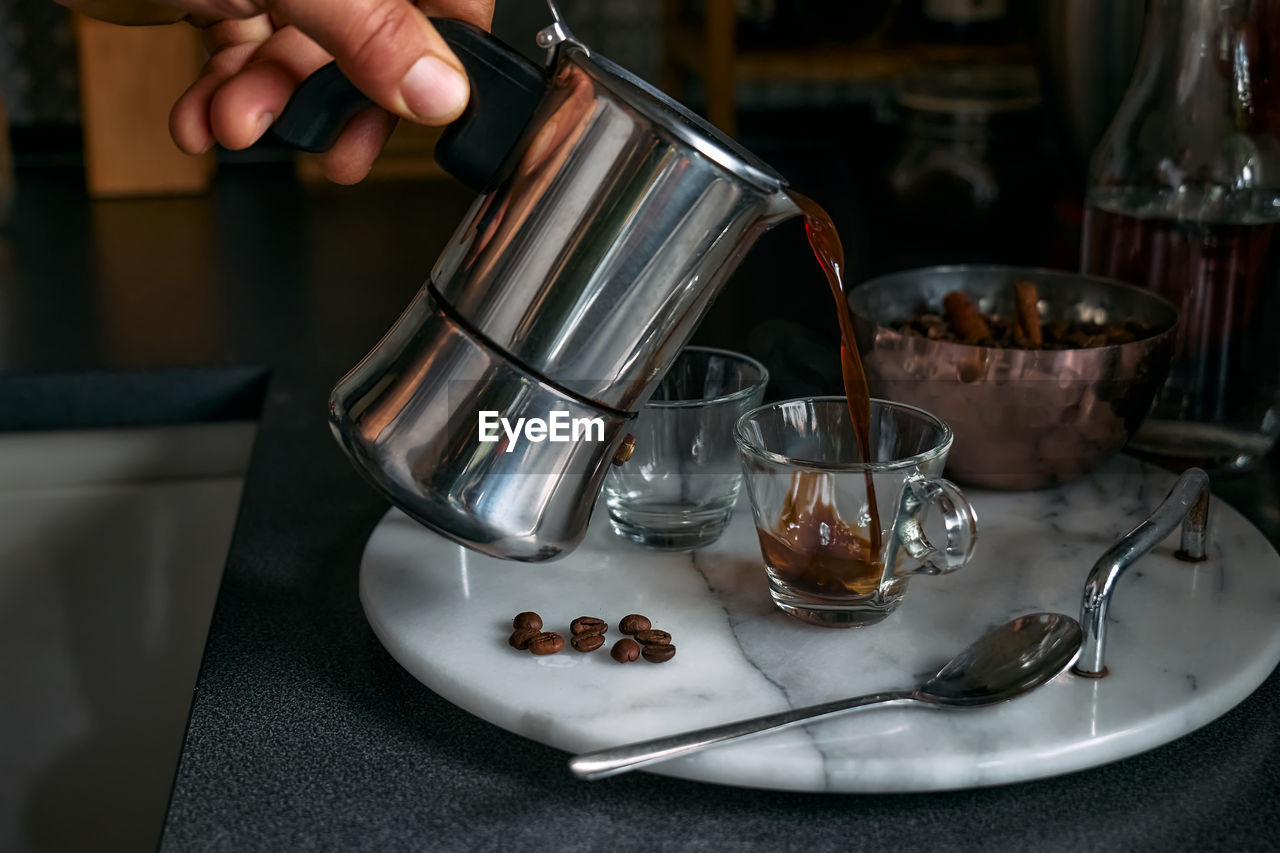 Man preparing classic italian coffee in the mocha. pouring coffee from moka pot to small coffee cup.