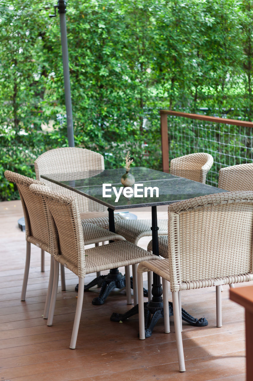 Empty chairs and table on floor against trees