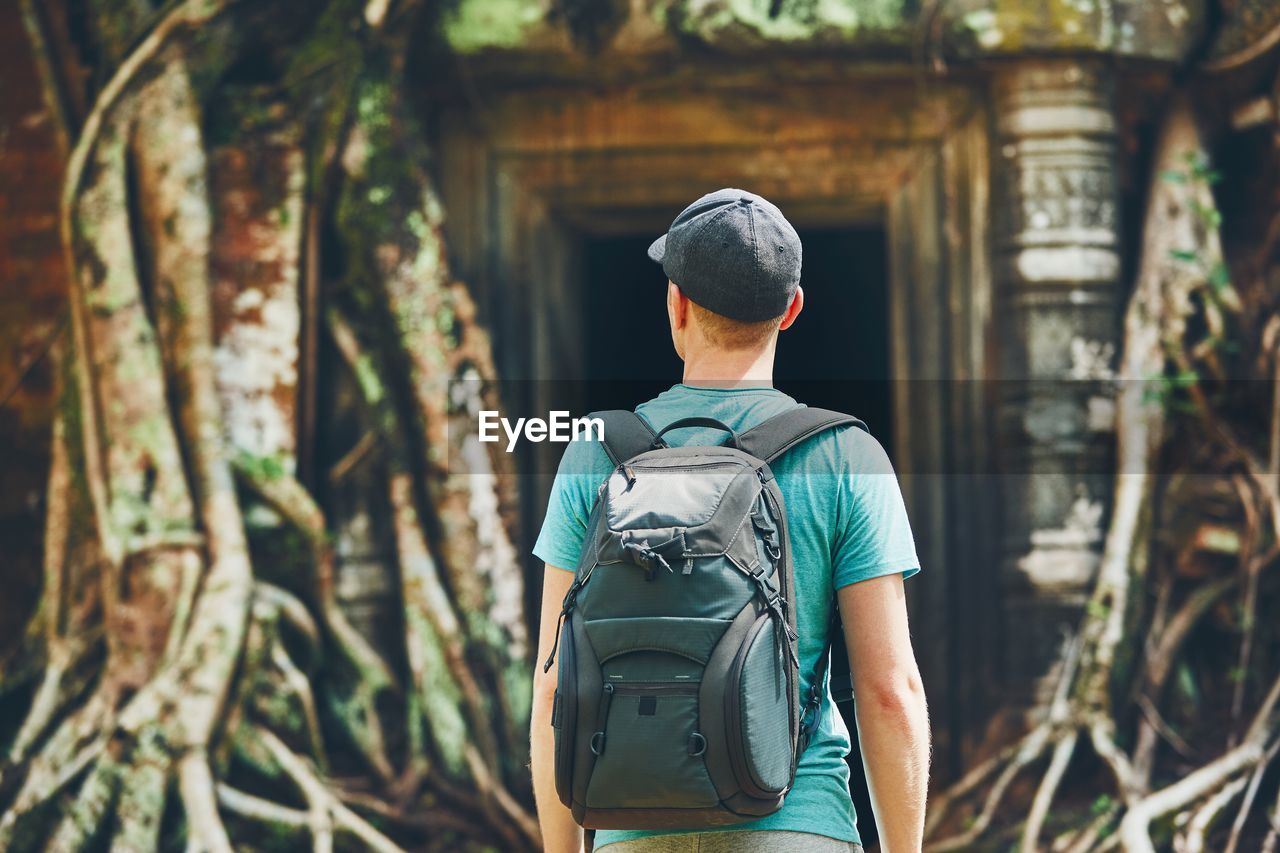 Rear view of young man with backpack standing in forest