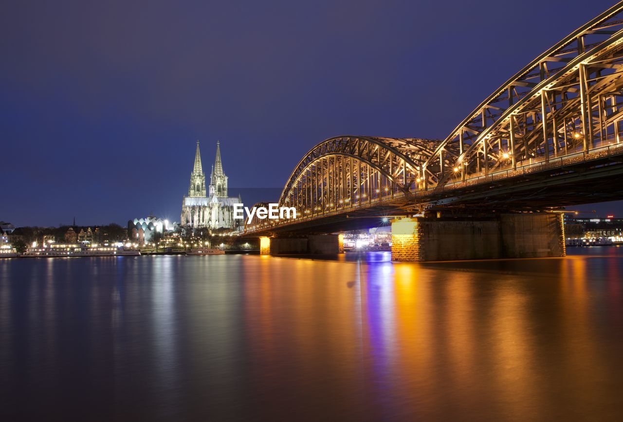 Illuminated hohenzollern bridge over city at night