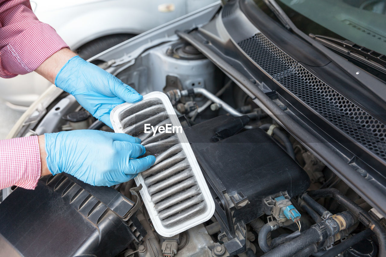 Cropped hands repairing car engine