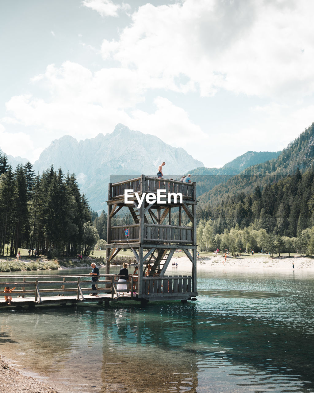 VIEW OF BUILDING BY LAKE AGAINST CLOUDY SKY