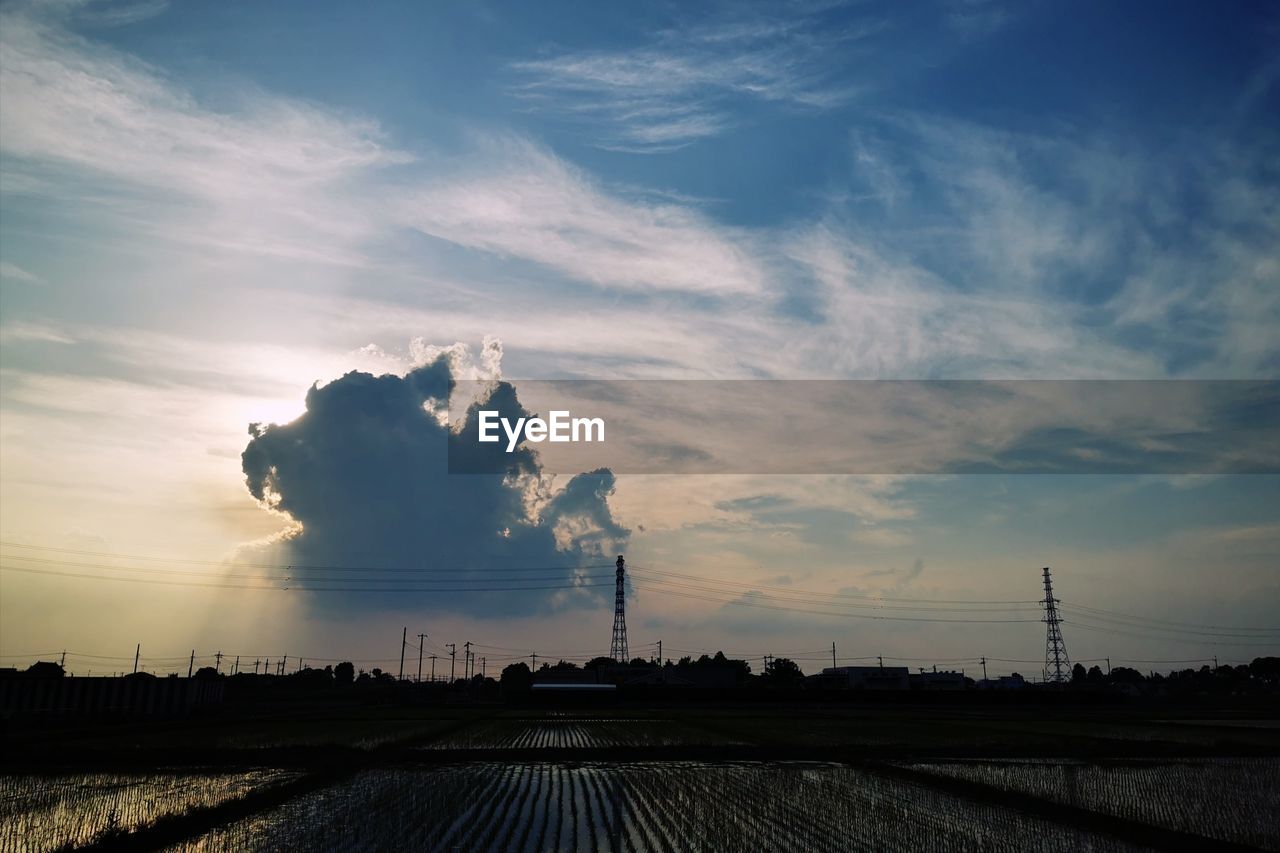 Smoke stack on field against sky during sunset