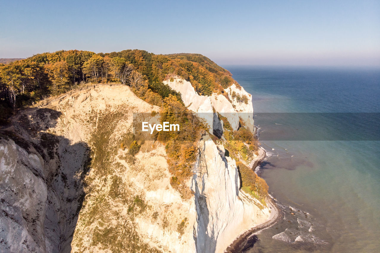 Rock formations by sea against clear sky