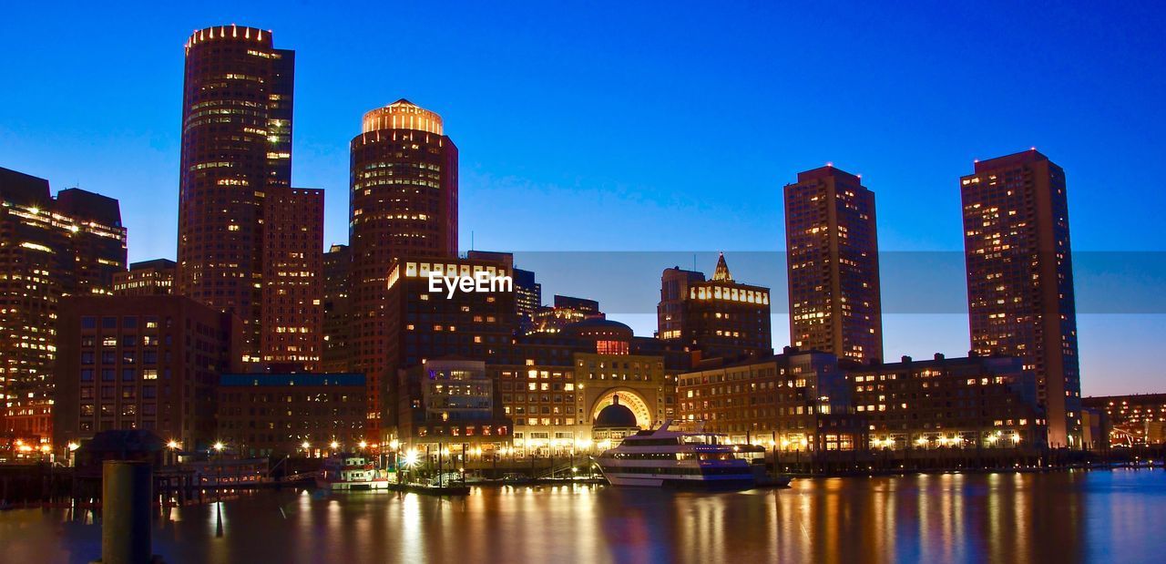 Illuminated buildings by city against sky at night