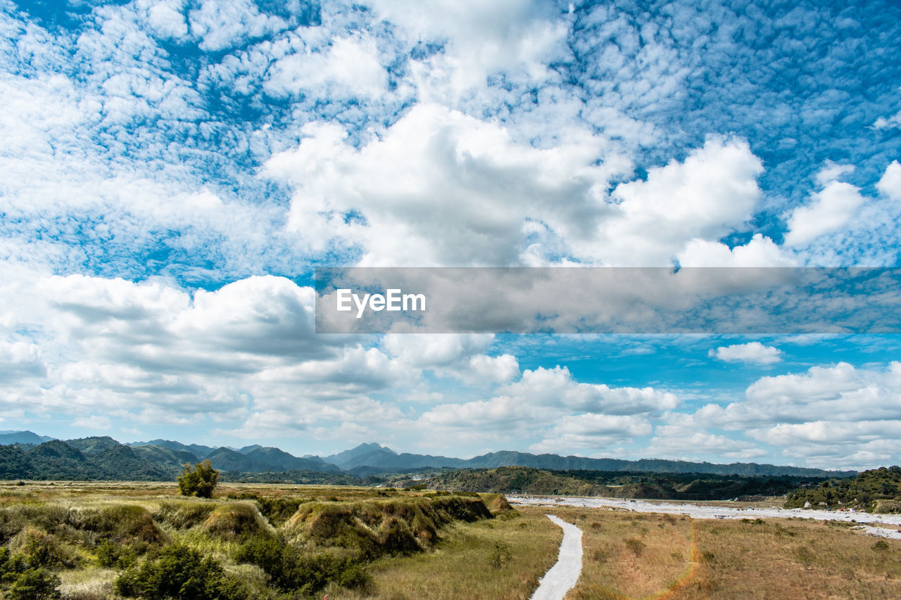 Scenic view of road amidst field against sky