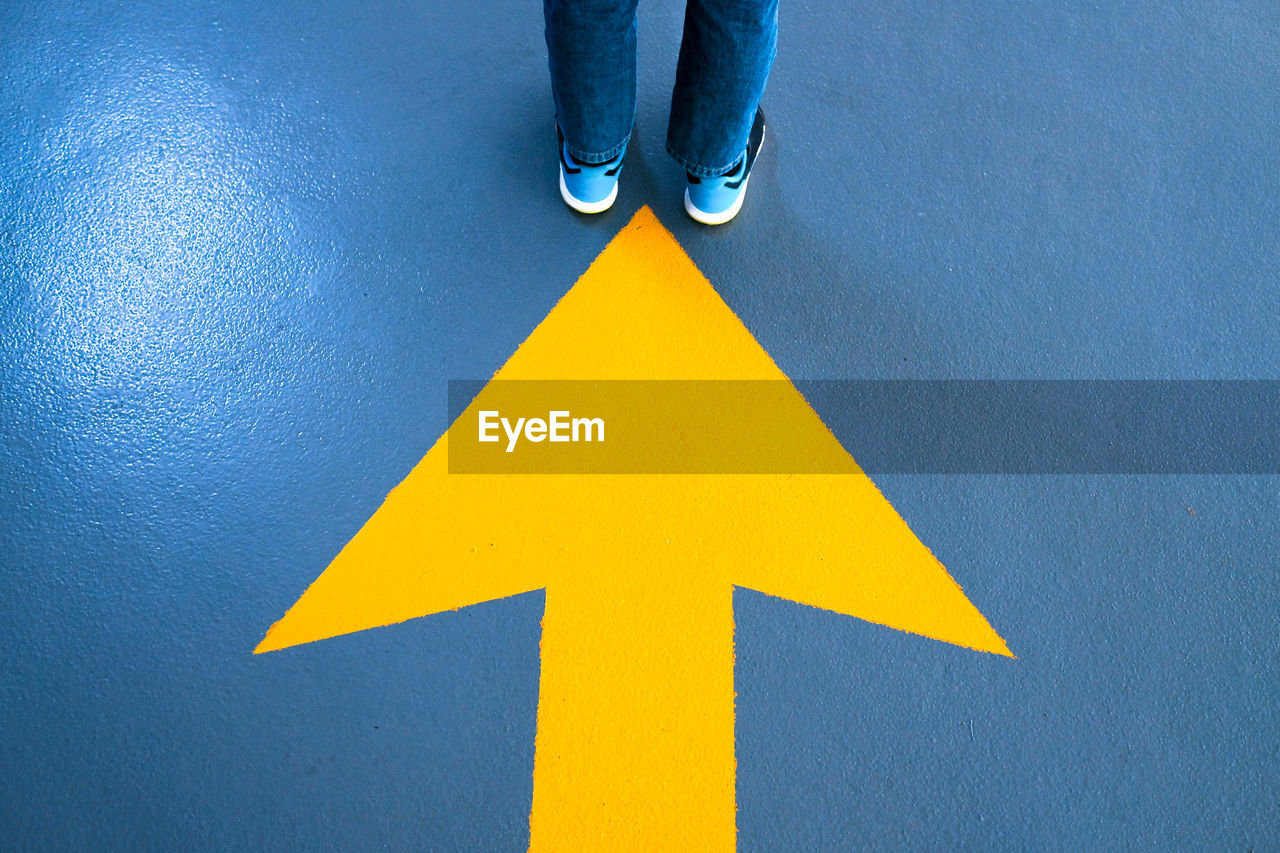 Low section of person standing on road sign