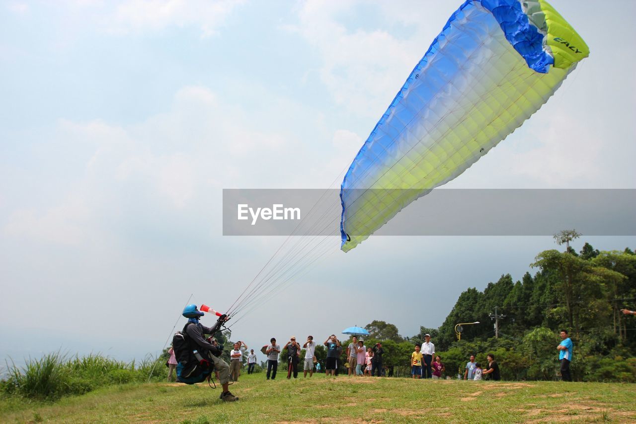 Man preparing for paragliding while people looking at him