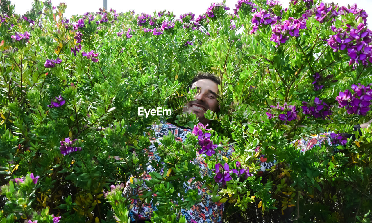 Portrait of smiling man amidst flowering plant