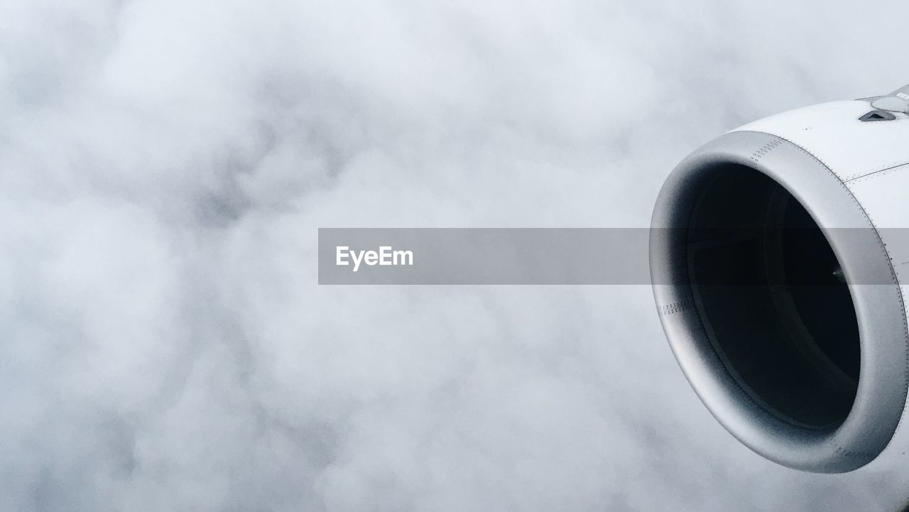 Cropped image of airplane against cloudy sky