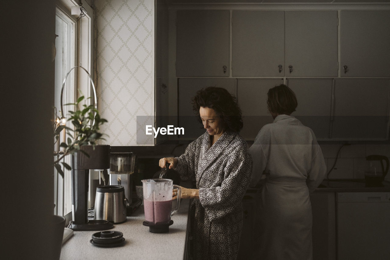 Lesbian couple making breakfast together in kitchen at home