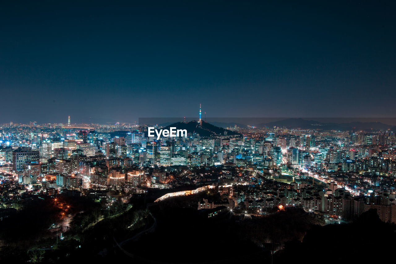 Illuminated cityscape against sky at night