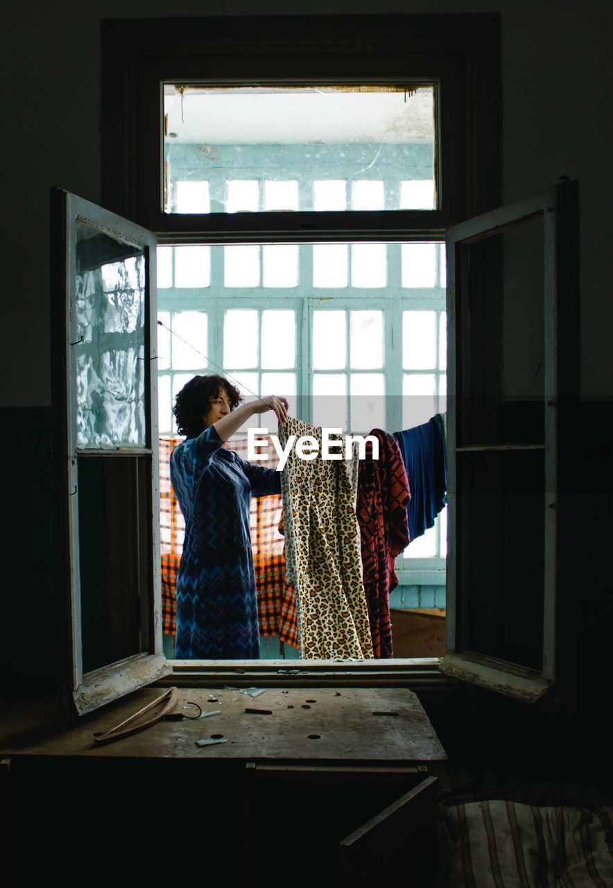 Rear view of woman looking through window