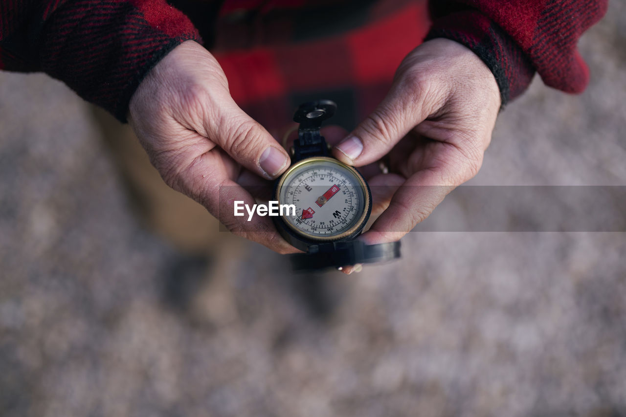 Cropped image of bushcrafter holding navigational compass while hiking