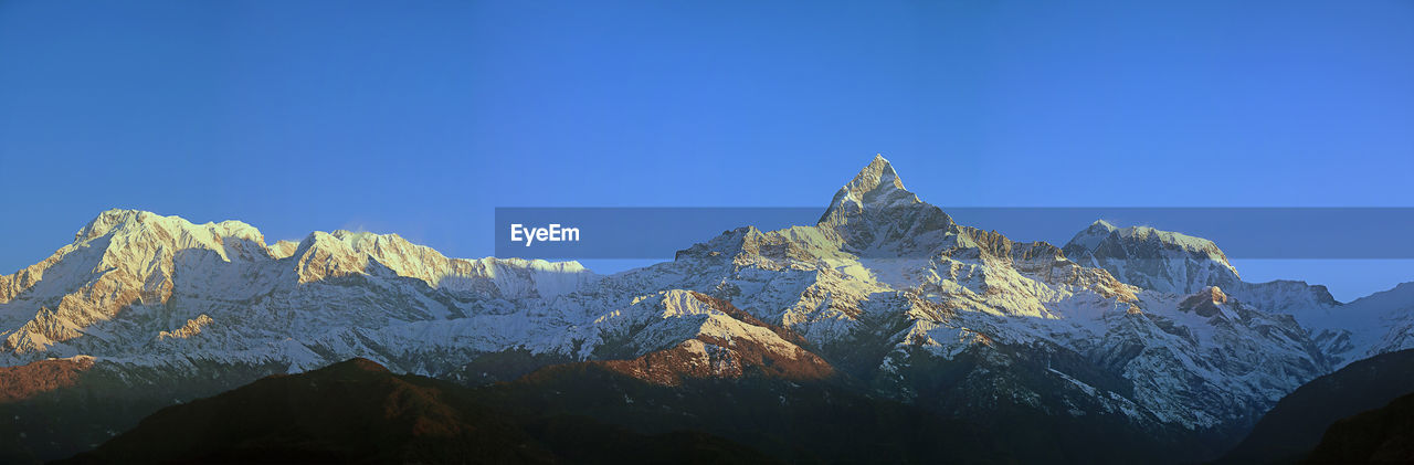 Scenic view of snowcapped mountains against clear blue sky