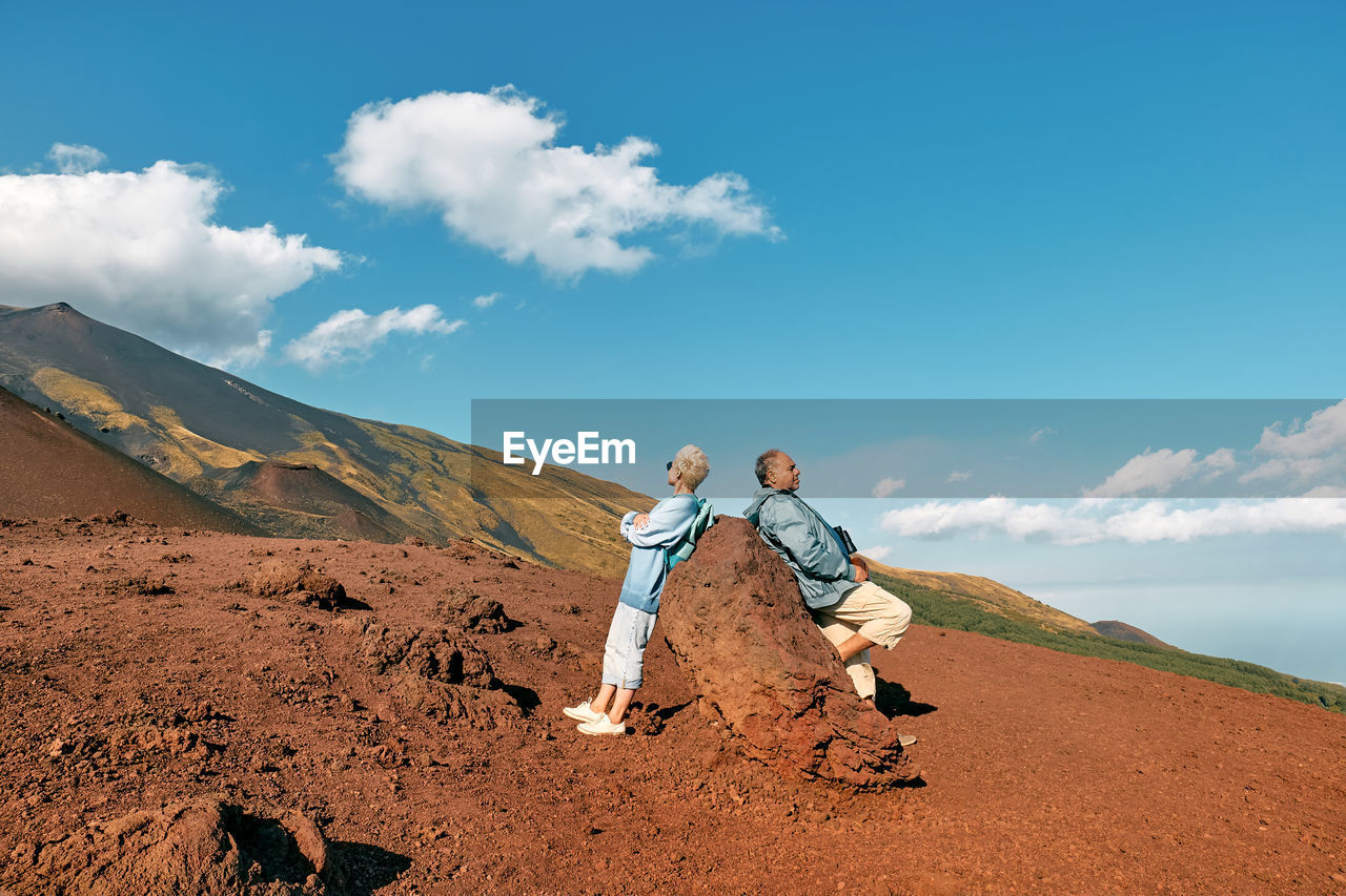 Tourist woman and man enjoying freedom, while admiring panoramic view of volcano etna.