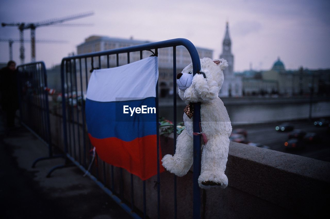 Teddy bear and russian flag on barricade against buildings in city