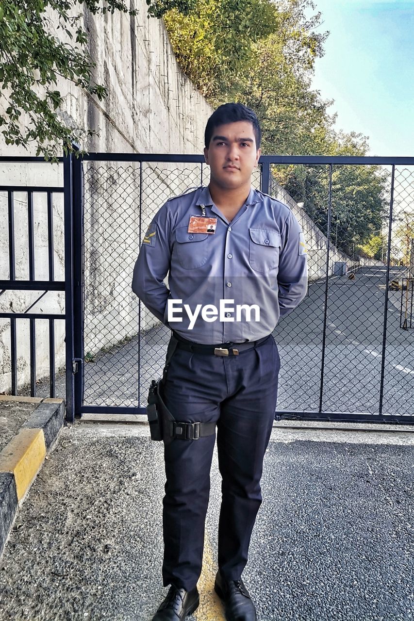 PORTRAIT OF A YOUNG MAN STANDING OUTDOORS