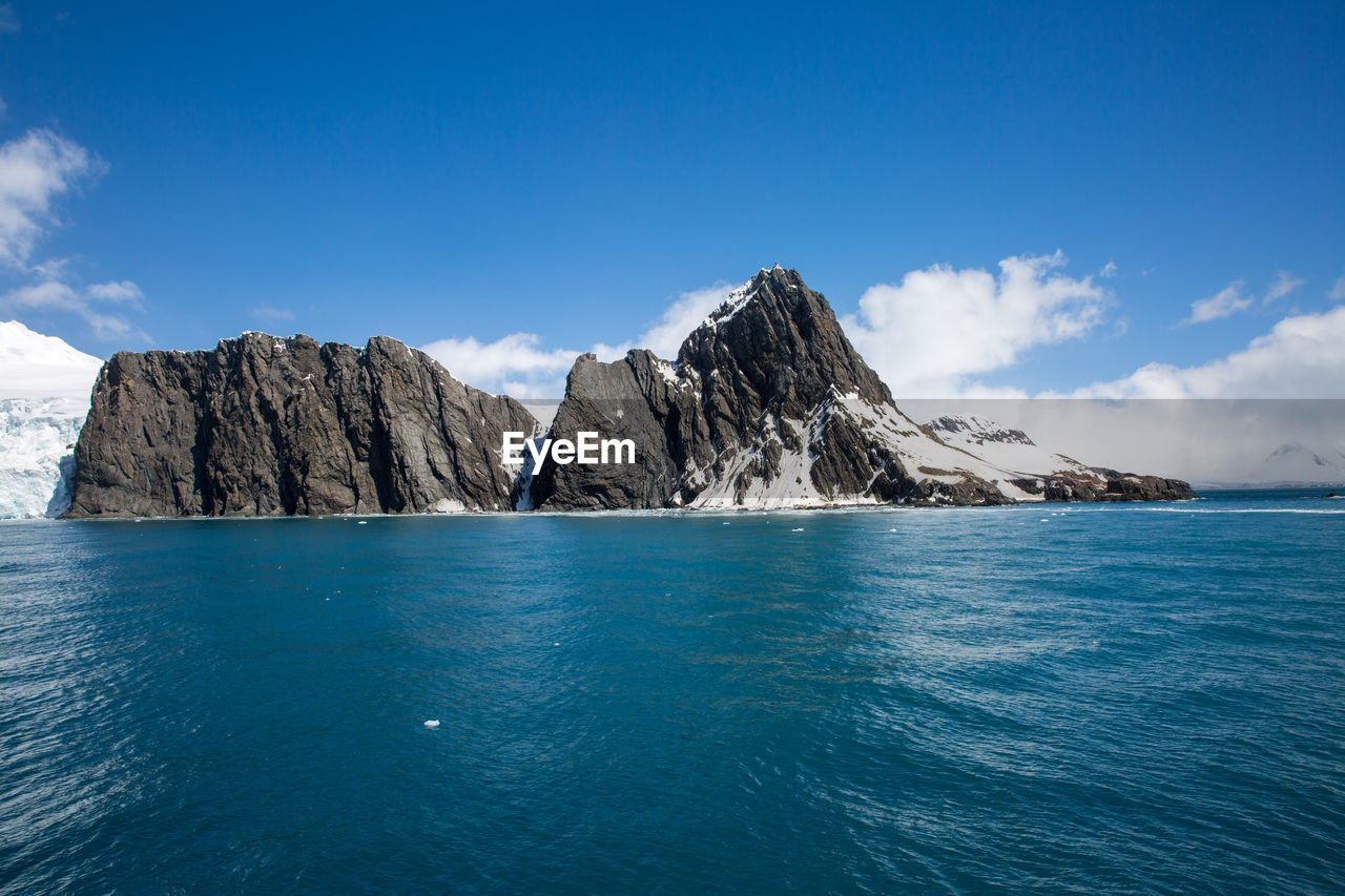 Panoramic view of sea and mountains against blue sky