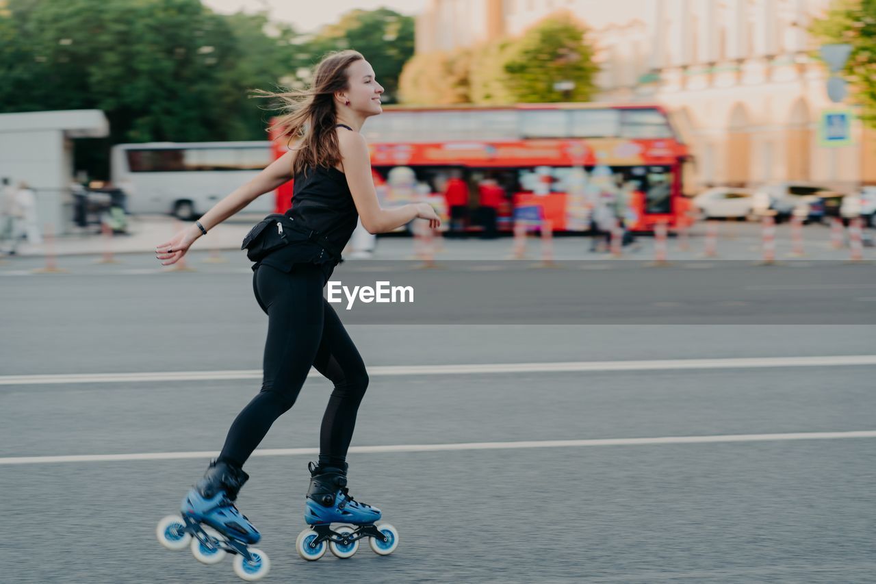 Full length of woman skateboarding on street in city