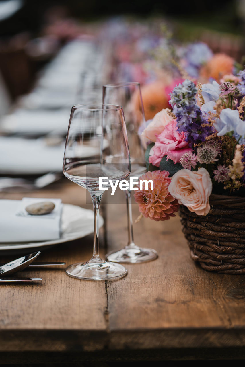 Beautiful wedding wooden table banquet decoration with flowers, wine glasses, roses and plate