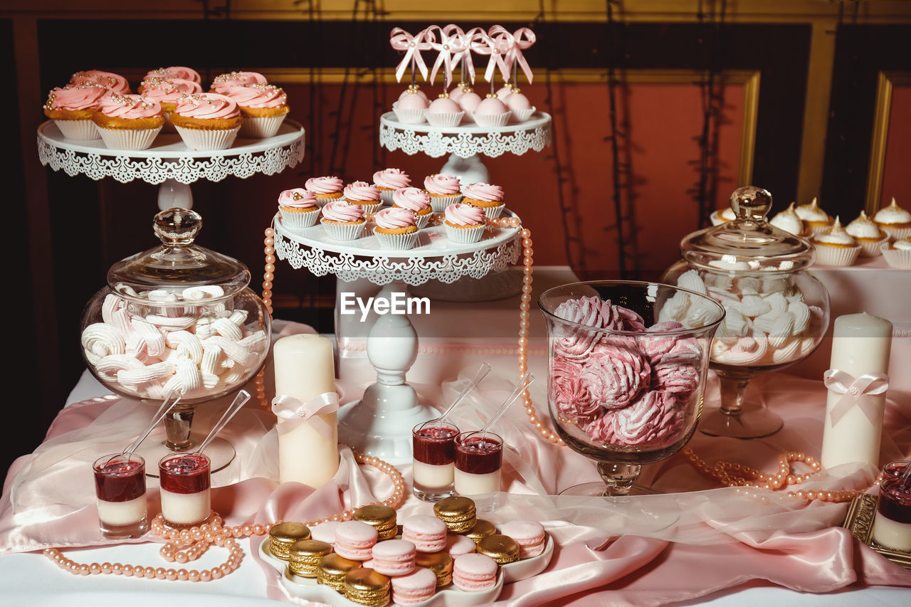 Cupcakes with pink cream and decorated with golden pastry beads on a white tray