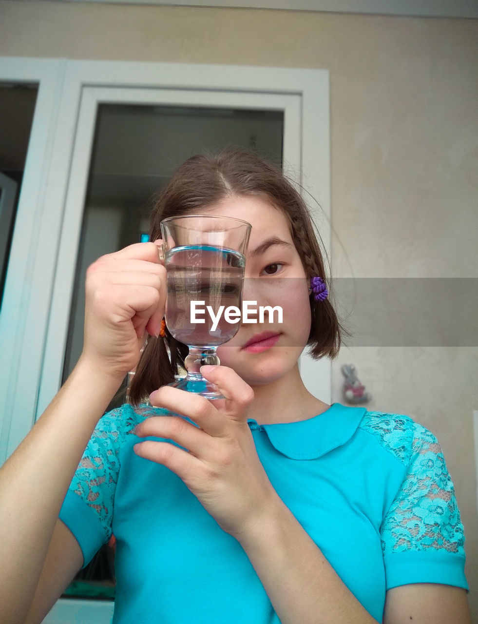 Low angle portrait of girl holding drinking glass against house