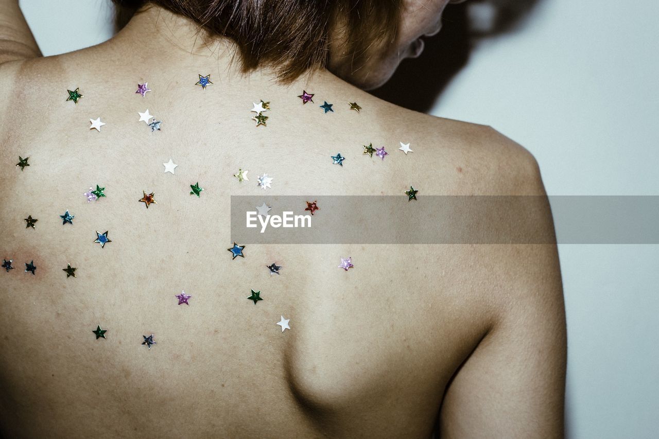Rear view of shirtless woman with colorful glitters