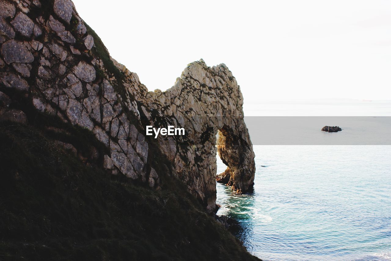 Rock formations by sea against clear sky