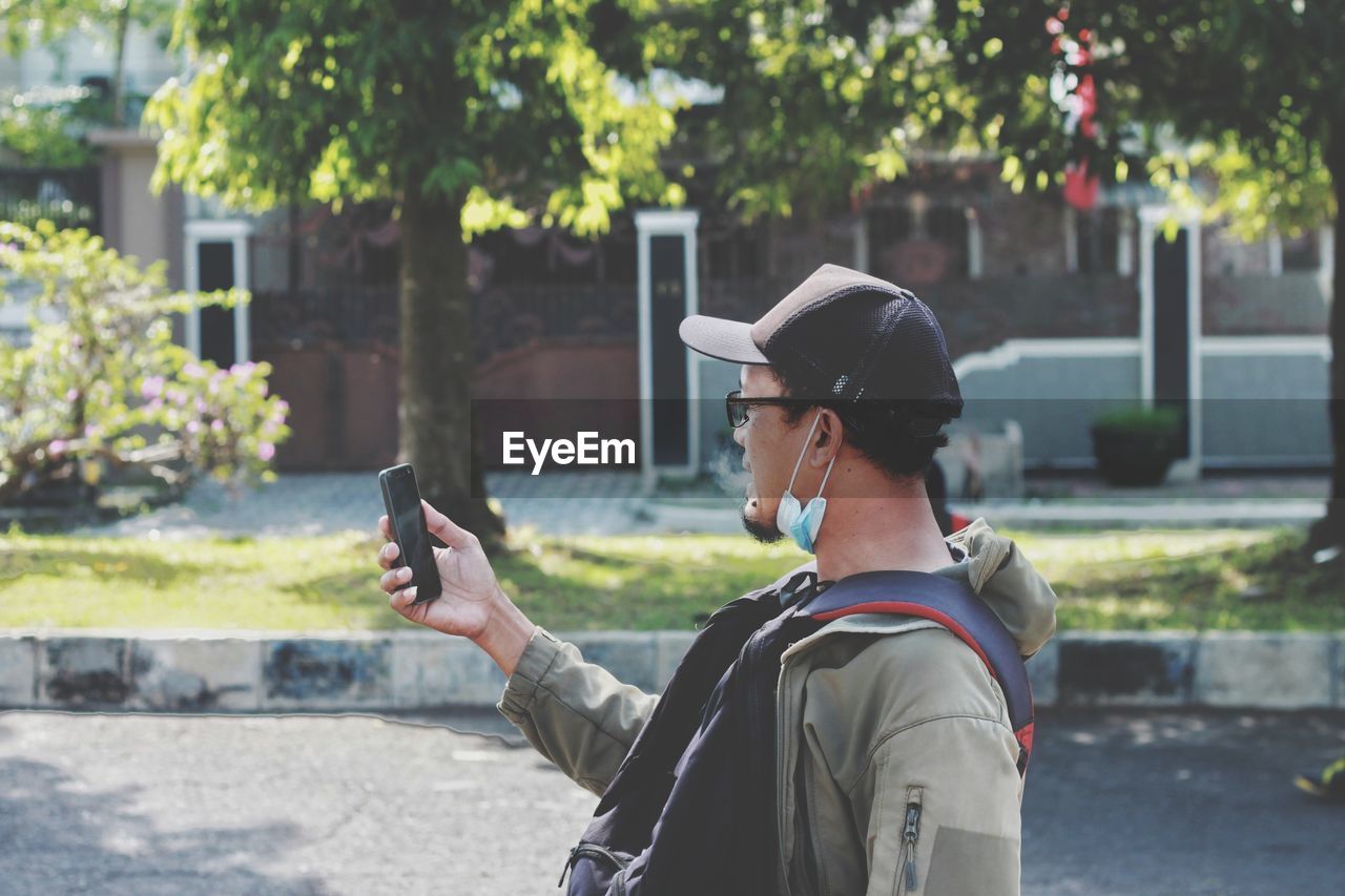 Side view of man photographing with mobile phone