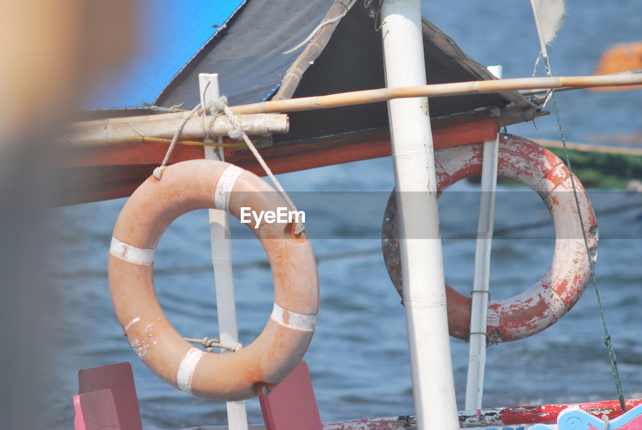 CLOSE-UP OF ROPE TIED TO RAILING AGAINST WATER