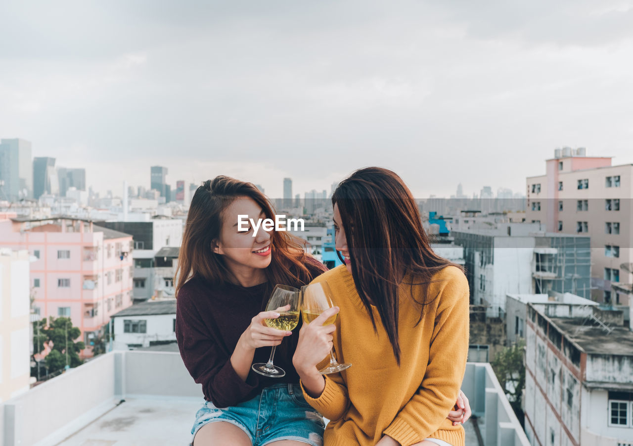 Female friends toasting wineglasses at building terrace in city