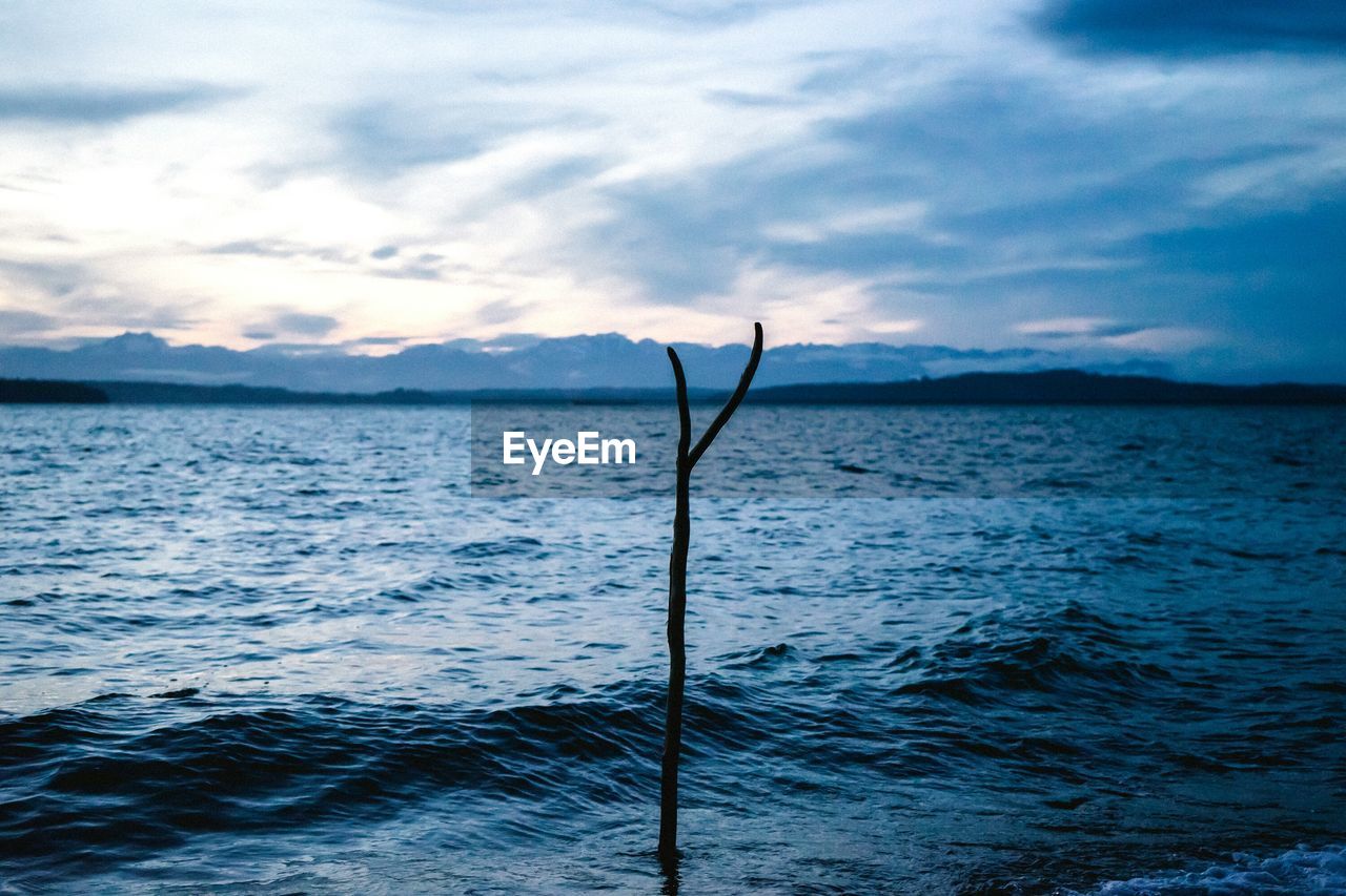 Scenic view of sea against cloudy sky during sunset