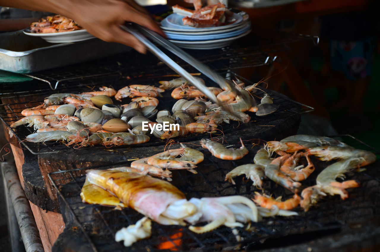 High angle view of person preparing seafood on barbecue grill