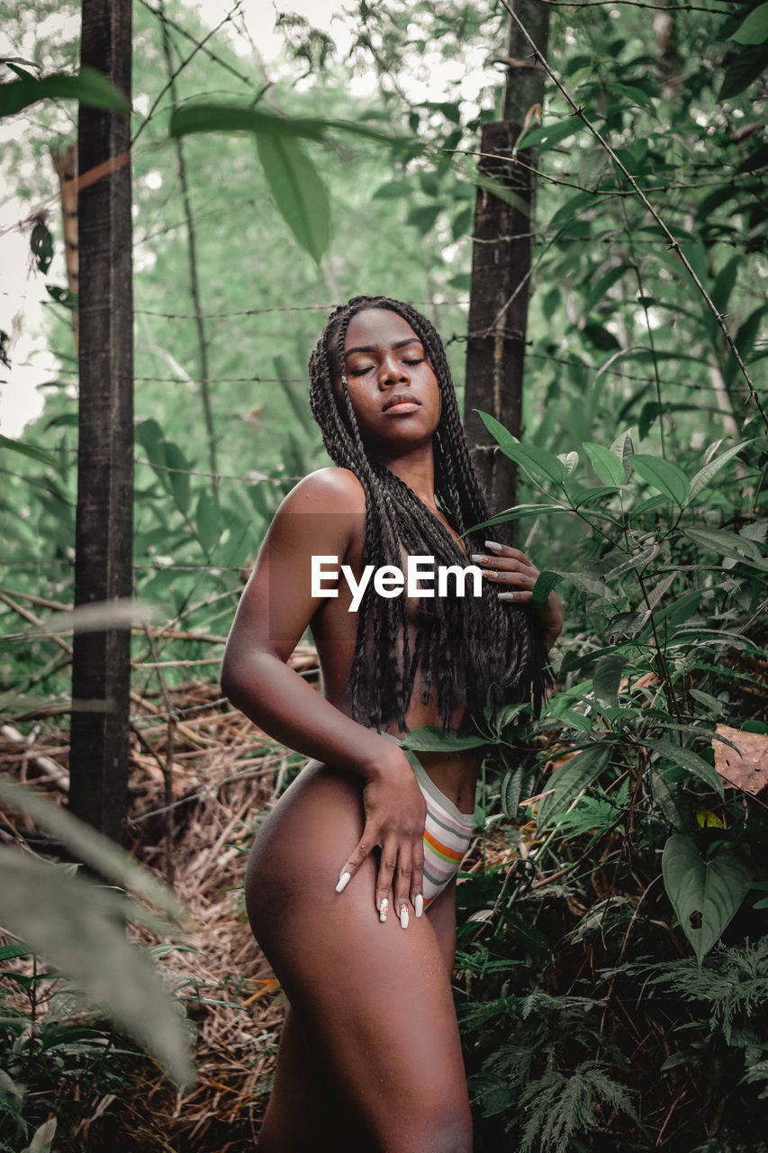 Portrait of young woman standing against plants