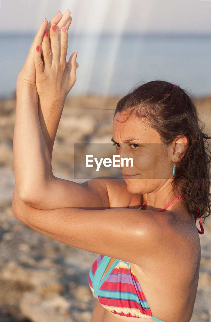 Woman exercising at beach against sky