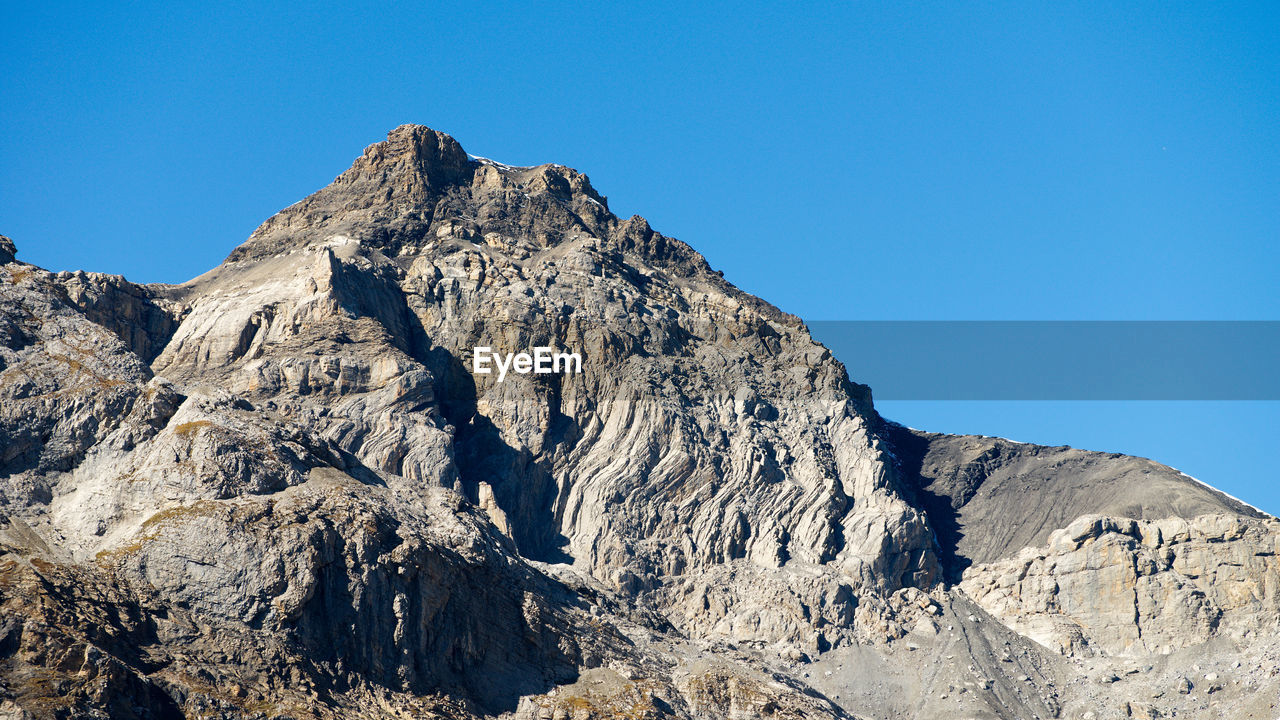 Low angle view of rock formation against clear blue sky