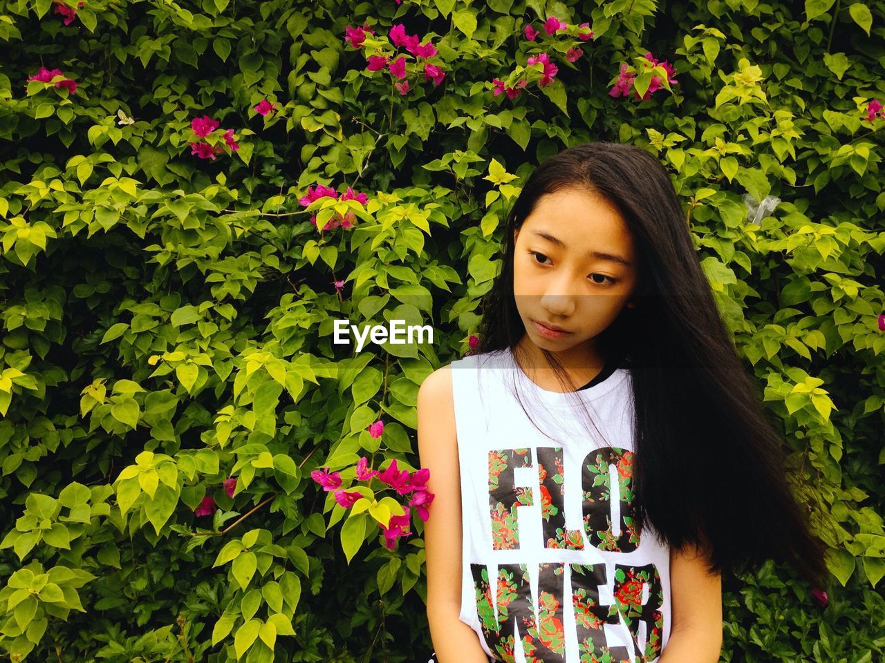 Thoughtful teenage girl sitting against plants