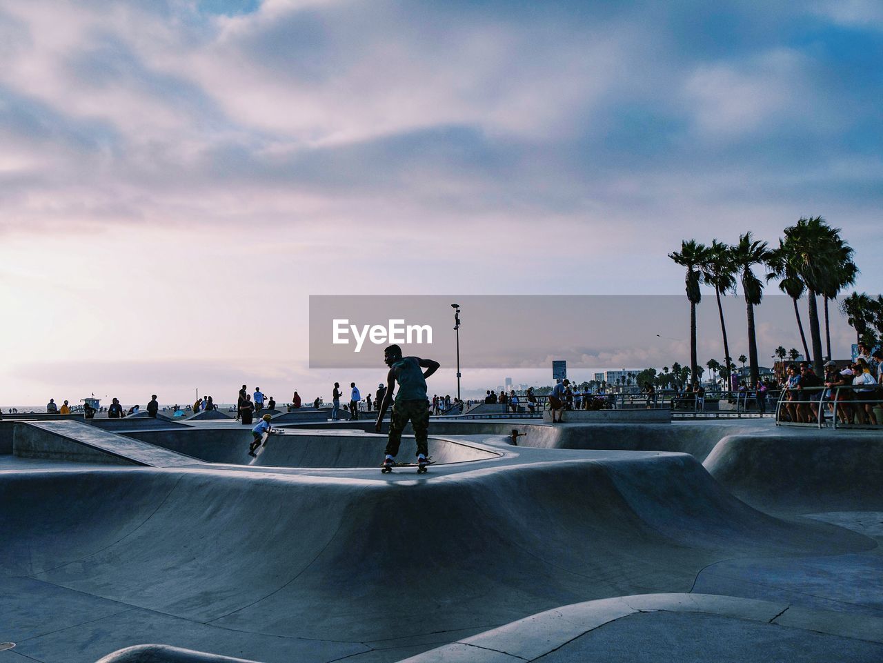 People at skateboarding park against sky during sunset