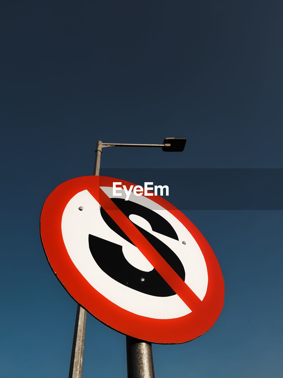 Low angle view of road sign and electric street lamp against blue sky