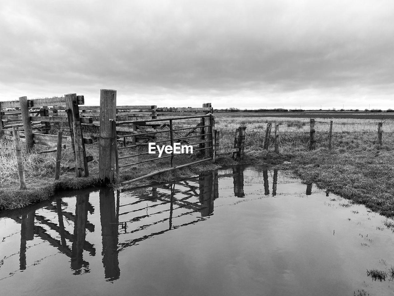 Wooden post and gate on water against sky