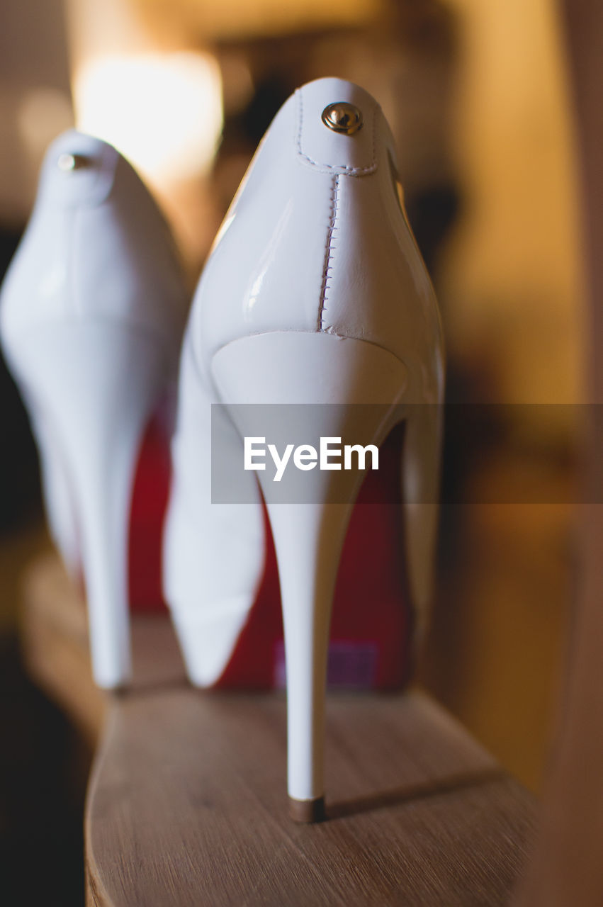 Close-up of white high heels on wooden table at home