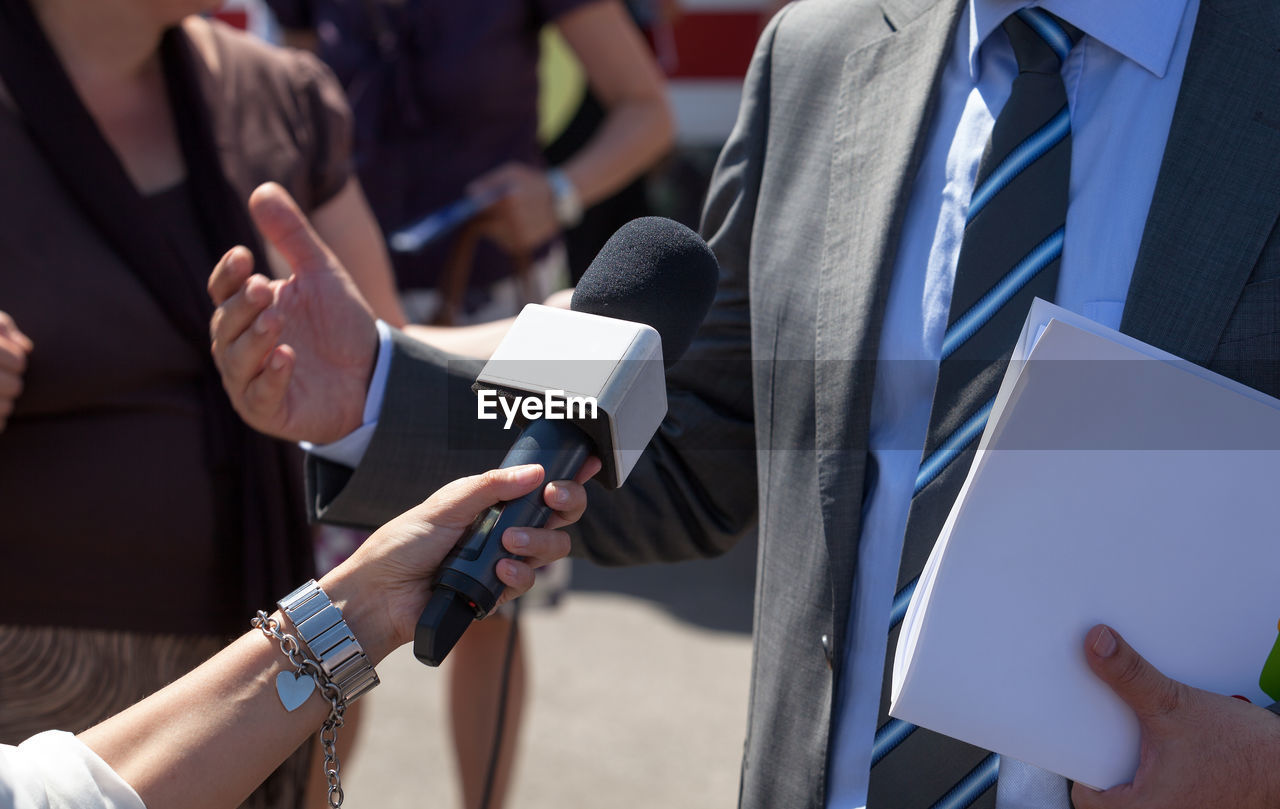 Cropped hand of female journalist interviewing businessman